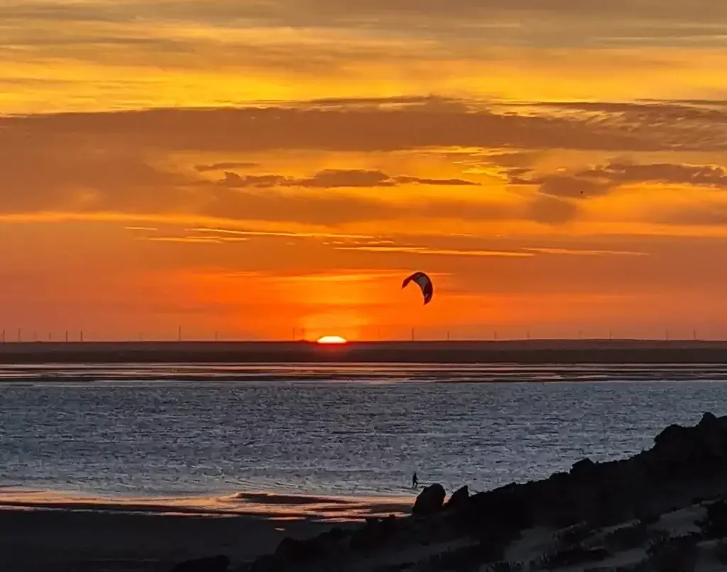 Kitesurfeur naviguant sur le lagon calme de Dakhla durant l'arrière-saison au coucher du soleil