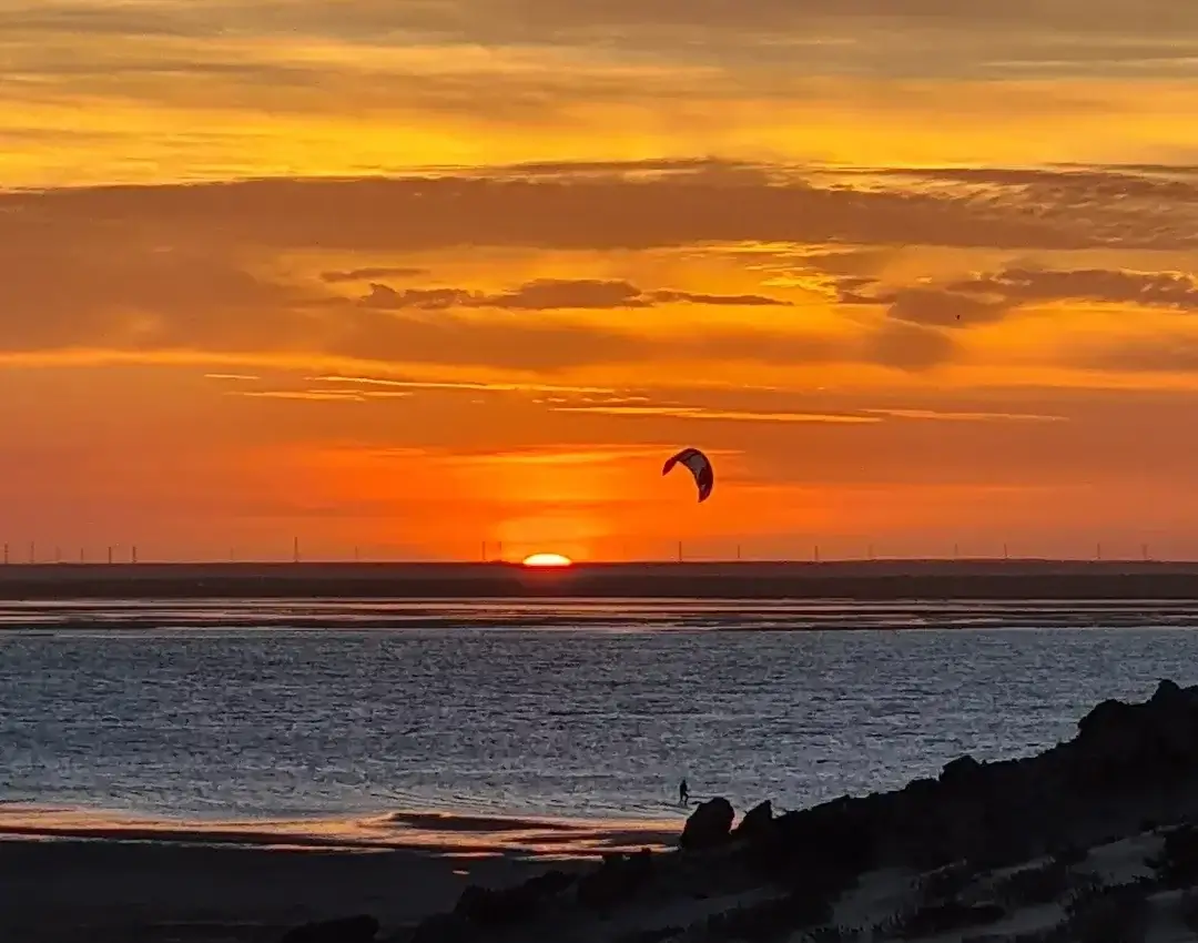 Kitesurfeur naviguant sur le lagon calme de Dakhla durant l'arrière-saison au coucher du soleil